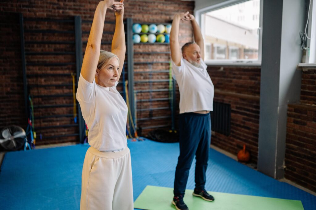 Senior couple stretching in gym.