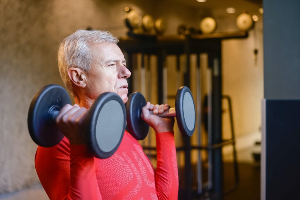 Senior man lifting weights at the gym.