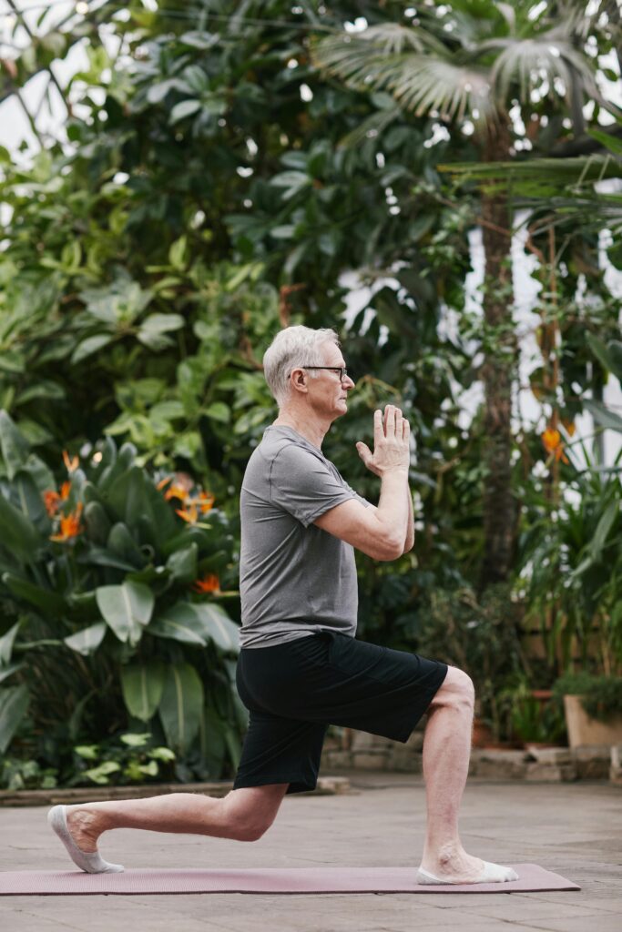 Senior man doing yoga in a garden.